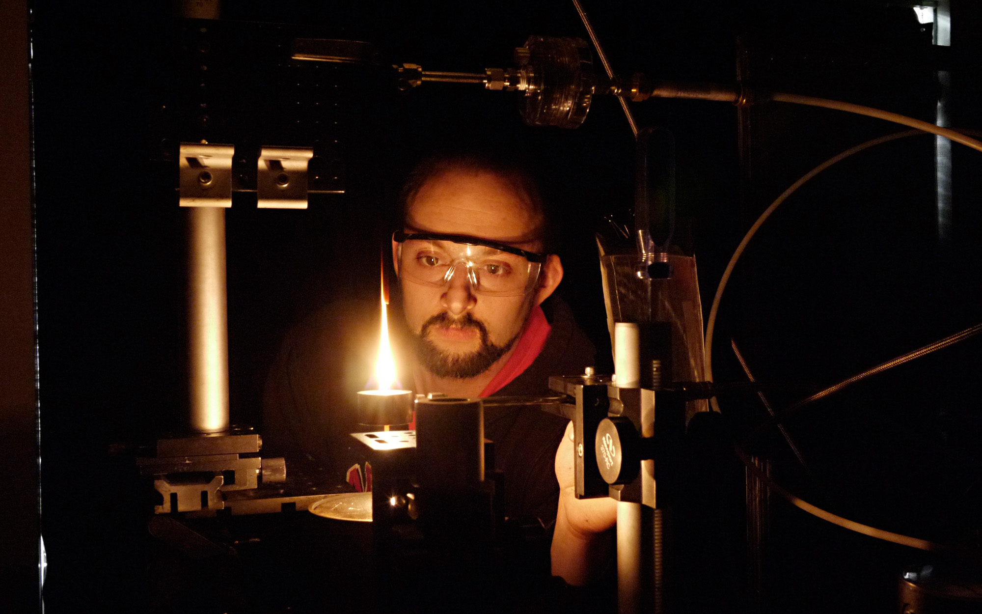 Student with goggles observing flame from up close.